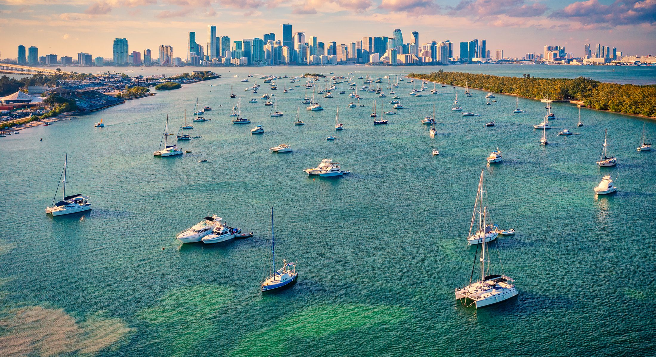 Miami skyline with boats on tranquil water.