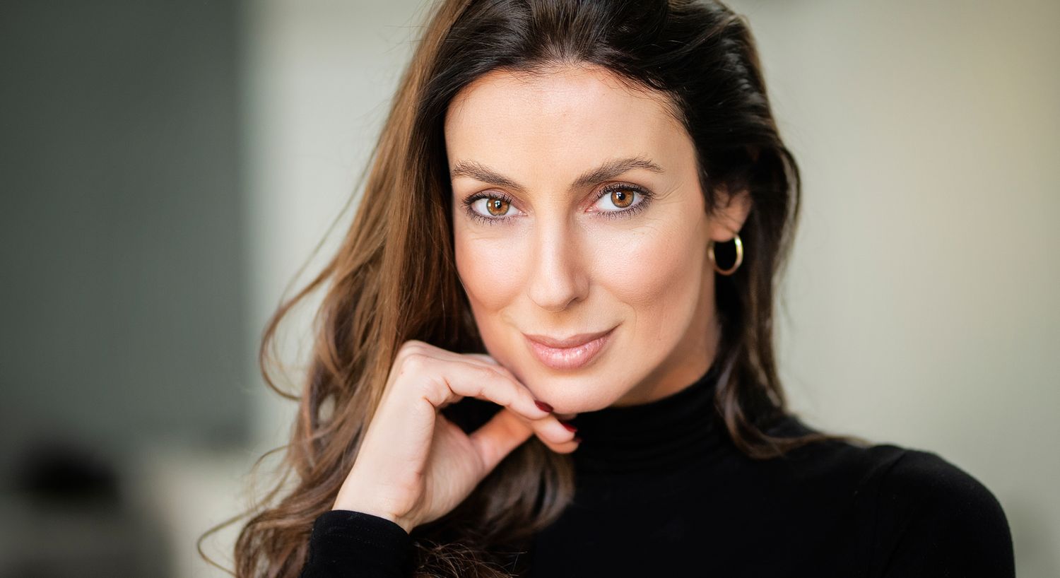 Woman outdoors with wavy hair and soft expression.